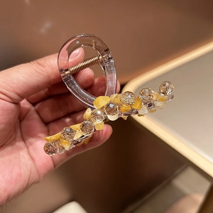 Détail de la pince à cheveux en acrylique faite main avec perles jaunes et ressort doré