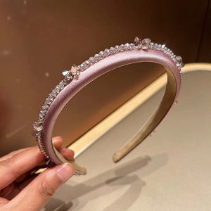 Detailed macro view of pink satin headband with hand-sewn crystals and rhinestones