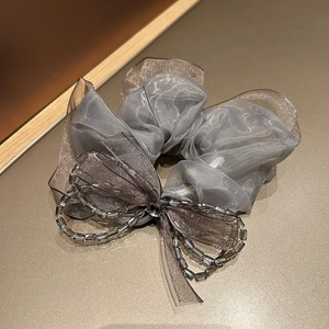 Detail of grey organza scrunchie with lace bow and elegant faceted bead chain accents
