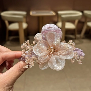 Dettaglio del fermaglio per capelli a fiore in organza fatto a mano con perle
