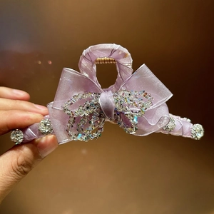 Detailed macro view of purple ribbon hair claw clip with crystal bow and gold metal spring