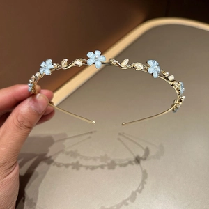 Détail du serre-tête doré avec fleurs bleues et petites perles dans un style champêtre