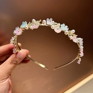 Close-up of elegant pearl headband with resin flowers and rhinestones on gold metal