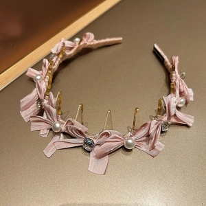 Detail eines rosa Seidenhaarreifs mit Schleife, Kunstperlen und glänzenden Straßsteinen