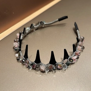 Detailed close-up of handmade headband featuring crystal stones and gothic metallic spikes