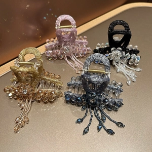 Close-up of four crystal tassel hair claws in gold, purple, black, and blue colors