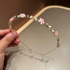 Détail d'un serre-tête à fleurs roses avec perles et cadre en métal doré pour femme