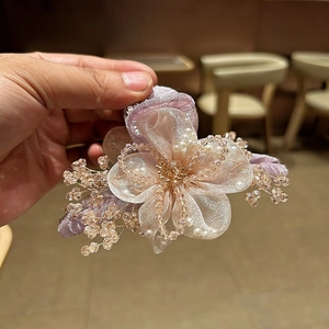 Dettaglio di fermaglio per capelli con fiore in organza rosa e perline di cristallo dorato