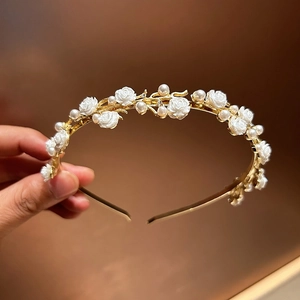 Macro detail of elegant golden alloy headband with white roses and high-luster pearls