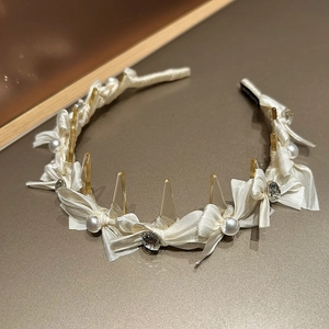 Detail eines cremefarbenen Haarreifens mit Perlen und Kristallen auf Satin-Stoffbezug