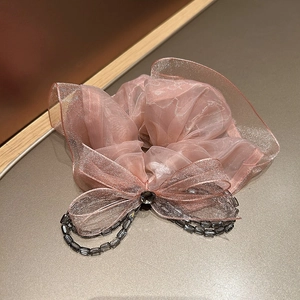 Detail of pink organza hair scrunchie with lace bow and dark grey beaded tassels