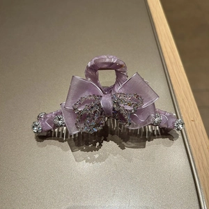 Close-up of elegant purple bow hair claw clip with sparkling rhinestones and crystals