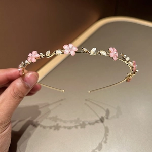 Détail de serre-tête en métal doré orné de fleurs roses et de perles blanches