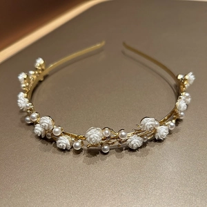 Close-up of golden metal headband featuring delicate white roses and glossy pearls