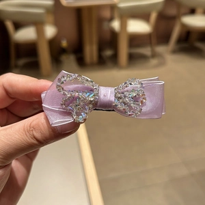 Detail of purple silk bow hair claw with shimmering colorful rhinestones handheld view