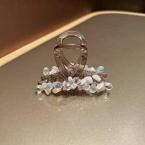 Vue détaillée des perles de cristal et pierres roses sur une pince à cheveux marron translucide