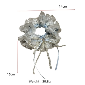 Vue détaillée du chouchou en dentelle grise avec glands en cristal et perles de nacre
