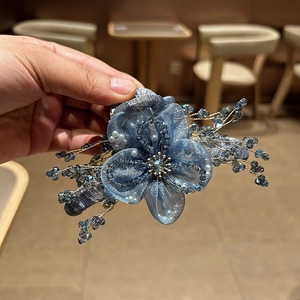 Dettaglio molletta per capelli a fiore in organza blu con perline di cristallo e oro