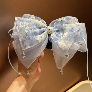 Détail du nœud en organza floral bleu clair avec perles et glands en cristal