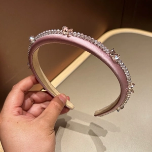 Detail of light pink satin wide headband with shimmering crystals and bow decoration