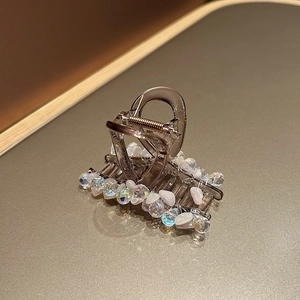 Détail de la pince à cheveux en résine marron fumé avec perles de cristal irisées et pierres