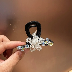 Détail d'une petite pince à cheveux en tissu noir ornée de perles de fleurs en cristal