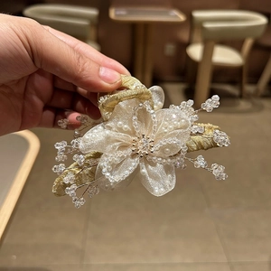 Dettaglio della pinza per capelli a fiore in organza con perle e cristalli su base dorata