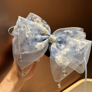 Détail d'un chouchou bleu clair en seersucker avec broderie florale et pendentif cristal