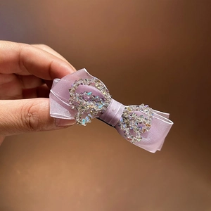 Close-up of purple satin bow hair claw with sparkling colorful rhinestones detailing
