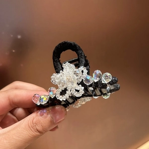 Détail de la pince à cheveux fleurie en cristal scintillant avec tissu noir tressé