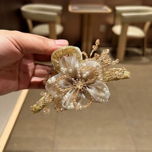 Dettaglio del fermaglio per capelli con fiori in organza fatti a mano e perle dorate