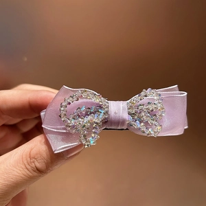 Macro shot of purple satin bow hair claw clip with colorful sparkling crystals