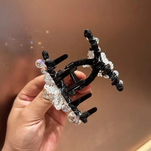 Détail de la pince à cheveux noire ornée de perles de cristal irisées et brillantes