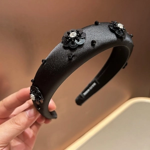 Close-up of black sequin flower headband with rhinestone center and thick sponge padding