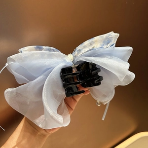 Détail de la pince à cheveux nœud en organza bleu clair avec des perles blanches élégantes