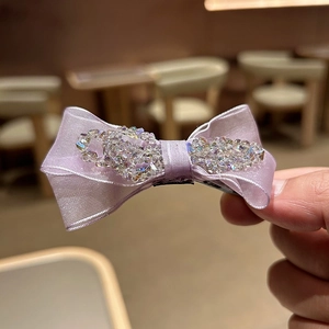 Macro detail of lavender mesh bow hair clip with shimmering crystal bead accents