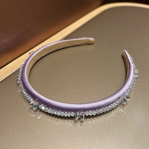 Detail of a purple satin headband featuring sparkling crystals and luxury vintage design