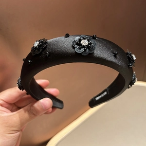 Close-up of handmade black sequin flower and crystal details on padded satin headband