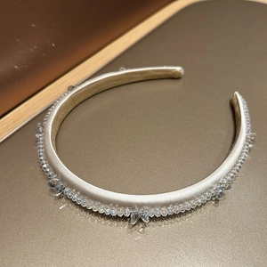 Detailed macro view of cream satin headband featuring luxury crystal bead embellishments