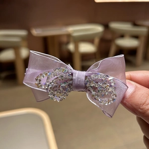 Close-up of a purple silk bow hair claw clip with sparkling multi-colored crystals