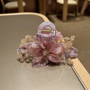Dettaglio della pinza per capelli a fiore in organza viola con cristalli color champagne