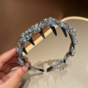 Close-up of grey-blue crystal beads and black fringe clips on a velvet hairband