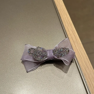 Close-up of a purple organza bow hair claw clip with sparkling rhinestones details