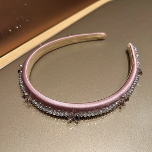 Detail of pink satin headband with purple crystal bow and shimmering beads