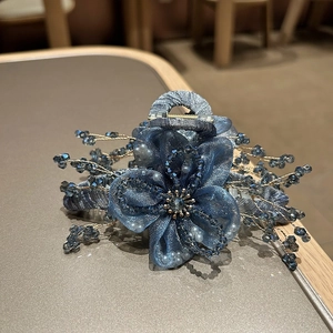 Dettaglio molletta per capelli con fiore in organza blu scuro, cristalli e filo dorato