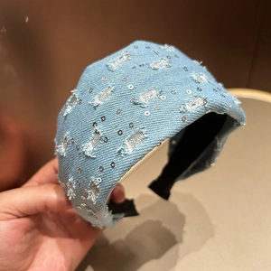 Detailed macro view of light blue denim headband with silver sequins and frayed edges