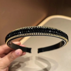 Close-up of black beaded headband with gold chain trim and sparkling crystal details