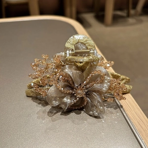 Dettaglio del fermaglio per capelli a fiore in organza fatto a mano con perle e ambra
