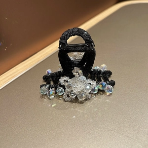 Gros plan d'une pince à cheveux noire en tissu ornée de perles de cristal pour femmes