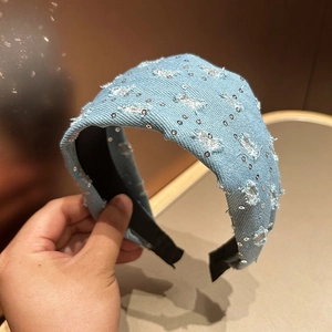 Detail of light blue denim headband with silver sequins and distressed fringe texture